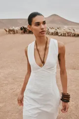 Vestido midi blanco con bordados florales perforados, escote en V, sin mangas y tirantes cruzados en la espalda.