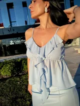Blusa celeste con breteles finos y volados en el escote.