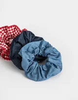 Set de tres scrunchies para el pelo, uno de denim azul oscuro, uno de denim azul claro y uno de tela a cuadros rojos y blancos con volados.