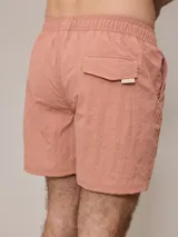 Short de baño azul marino con cintura elástica ajustable con cordón y logo de la marca bordado en rojo en la pierna izquierda.