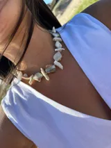 Collar corto con cuentas irregulares de nácar en tonos blanco, beige y marrón claro. Se cierra con cadena de acero quirúrgico y ganchito para regular el largo.