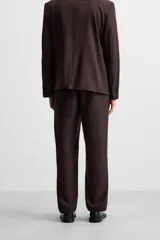 Pantalón de vestir color marrón oscuro, de corte recto, con bolsillos laterales y traseros de doble vivo. Cierre frontal con cremallera y botón.