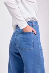 Pantalón jean ancho de tiro alto, color azul medio, con terminación desflecada en el ruedo.
