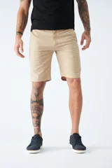 Bermuda color beige de corte chino, con bolsillos laterales, cierre con cremallera y botón, presillas para cinturón y logo bordado. Confeccionada en lino y algodón.