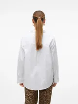 Camisa blanca oversize con hombros caídos y bolsillo frontal.