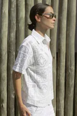 Camisa blanca con diseño calado, de corte recto, cuello camisero y mangas cortas.