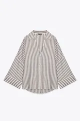 Camisa a rayas verticales color marrón y blanco, de corte holgado, con cuello solapa, cierre frontal con botones y mangas anchas por debajo del codo.