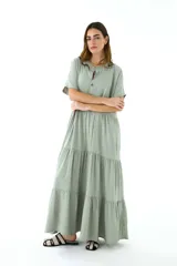 Vestido largo color verde salvia, de lino, con cuello mao, mangas cortas y corte escalonado con volados.