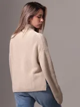 Sweater color beige de tejido de punto grueso con cuello alto y corte relajado.
