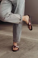 Sandalias tipo ojotas con base acolchada y estampado animal print de vaca en marrón y blanco.