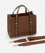 Bolso satchel mediano color marrón, confeccionado en poliuretano, con correa de mano con detalles de hebilla y costura, asa larga desmontable con gorgorão y cierre por cremallera.