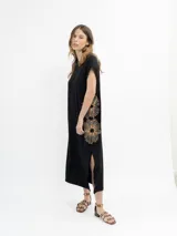 Vestido largo gris con bordado floral blanco, corte recto y mangas cortas. Presenta aberturas laterales en el ruedo.