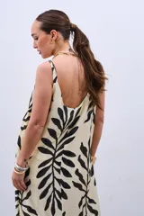 Vestido largo color crudo con estampado de hojas negras, de corte suelto y breteles finos.