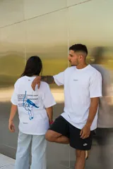 Remera blanca de algodón con estampado en la espalda de una mano azul y texto en negro.