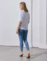 Blusa blanca de algodón marca Zac & Rachel, con cuello a la base, escote en V, abertura central con botones y sisa con aplique calado.