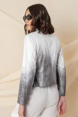 Chaqueta corta de cuero ecológico con diseño degradado de blanco a gris. Tiene cuello tipo solapa, cierre frontal asimétrico con broche y bolsillos con cierre.