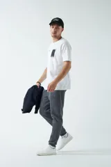 Remera verde militar de corte oversized, con cuello redondo y mangas cortas. Presenta un estampado con texto y figuras geométricas en el frente.