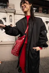 Campera bomber larga color negro, de nylon, con cierre frontal y bolsillos laterales.