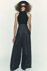 Top negro de cuello halter con cierre de botones en la parte trasera del cuello y espalda descubierta.