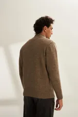 Campera de lana color crema, tejida con cierre delantero, cuello alto y bolsillos delanteros.