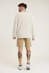 Sweater de punto color crema con cuello alto y cierre de cremallera parcial. Diseño de corte holgado y mangas largas.