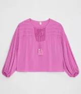 Blusa tipo blusón color rosado, de viscosa, con cuello redondo, manga larga acampanada, pliegues en los hombros, detalle de entredós en el escote y tiras de ajuste con borla.