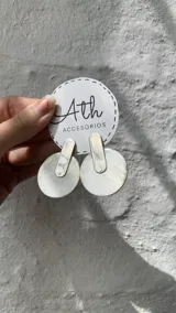 Aros colgantes con forma geométrica, hechos con guampa y detalles metálicos dorados o plateados.