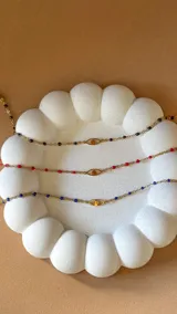 Pulsera dorada de acero con cadena de eslabones y cuentas de colores, con dije central de ojo turco.