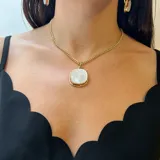 Collar con cadena de eslabones dorados y dije rectangular de nácar blanco con bordes irregulares y engaste dorado.