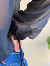 Blusa de gasa azul marino traslúcida con volados en los hombros y mangas largas abullonadas.