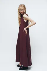Vestido midi negro de cuello redondo y sin mangas. Corte amplio y fluido, con bolsillos laterales ocultos y cierre trasero con cremallera invisible.