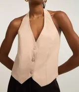 Blusa estilo chaleco color beige, de sastrería, con escote en pico, botones delanteros y espalda ajustable.