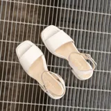 Sandalias de cuero color marrón con plataforma y tacón cuadrado. Tiras anchas sobre los dedos y tobillo con hebilla ajustable.