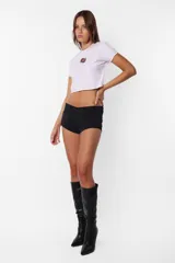 Remera corta blanca tipo baby tee, de cuello redondo y mangas cortas, confeccionada en jersey de algodón. Detalle de costuras rojas en toda la prenda y estampa de flecha con rosa en el delantero.