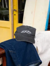 Gorra de mezclilla negra con visera curva y logo bordado en blanco.