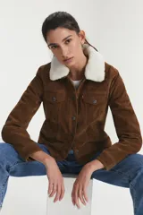 Campera Levi's color marrón con forro de sherpa blanco en el cuello. Es de gamuza sintética con cierre de botones y bolsillos en el pecho.