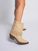 Bota corta de cuero color marrón con tachas plateadas, taco cuadrado y punta fina.