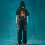 Remera oversize negra con efecto acid wash y estampa frontal con una silla y el texto 'Kaboa Industries. Sin siesta no hay fiesta'.