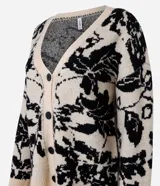 Cardigan largo de punto color beige con estampado floral negro, escote en V y cierre abotonado.