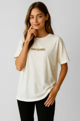 Remera color crema de algodón con estampado frontal con la frase "Stay Classic" en color marrón. De corte holgado y cuello redondo.