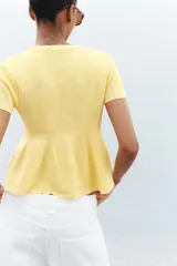 Chaqueta color amarillo claro de tejido de punto, con cuello redondo, manga corta, corte peplum y cierre frontal con botones.