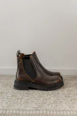 Bota Chelsea de cuero negro con elástico lateral y suela track.