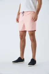 Short de baño color salmón con estampado de líneas curvas en relieve. Tiene cintura elástica con cordón ajustable, dos bolsillos laterales y uno trasero.