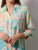 Camisa estampada con hojas en tonos celeste, naranja y verde. Tiene cuello con solapa, abertura central con botones, bolsillos aplicados en la parte delantera y mangas 3/4 con lazo.
