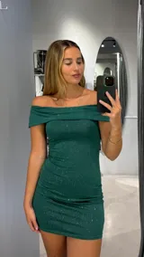 Vestido corto de fiesta color verde esmeralda con brillos, escote off-shoulder y corte ajustado al cuerpo.