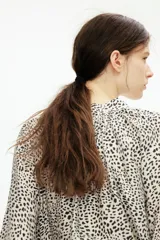 Blusa oversized con cuello elevado fruncido, abertura en V adelante y bajo recto. Mangas globo largas de corte raglán con abertura y botón en los puños.
