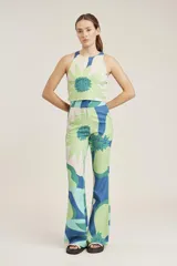 Top corto tipo crop top, sin mangas y con cuello halter. Presenta un estampado grande de flores en tonos verde claro, verde azulado y beige/crema.