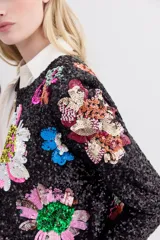 Saco corto negro con bordado de lentejuelas con forma de flores de colores. Tiene cuello redondo y ganchos invisibles al frente.