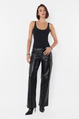Pantalón negro de cuerina, de corte recto, tiro medio-bajo, con bolsillos delanteros y traseros, presillas en la cintura y cierre metálico.