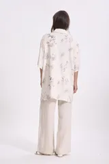Camisa beige con estampado abstracto en tonos grises, azules y marrones. Corte oversize, mangas cortas y cuello clásico.